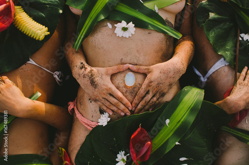Beautiful naked female body covered with tropical flowers and plant