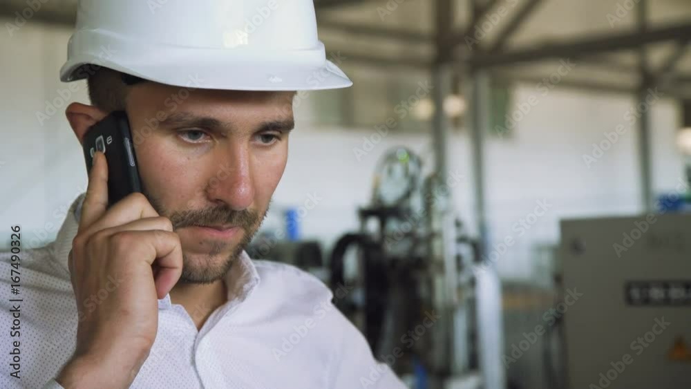Handsome manager speaking on the phone with emotions in the factory 4K Handsome manager speaking on the phone with emotions in the factory 4K