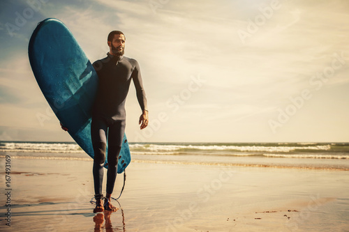 Portrait of surfer man with surf board on the beach. Mixed race black skin and beard. Summer sport activity