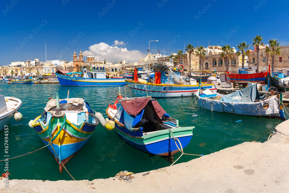 Naklejka premium Traditional eyed colorful boats Luzzu in the Harbor of Mediterranean fishing village Marsaxlokk, Malta