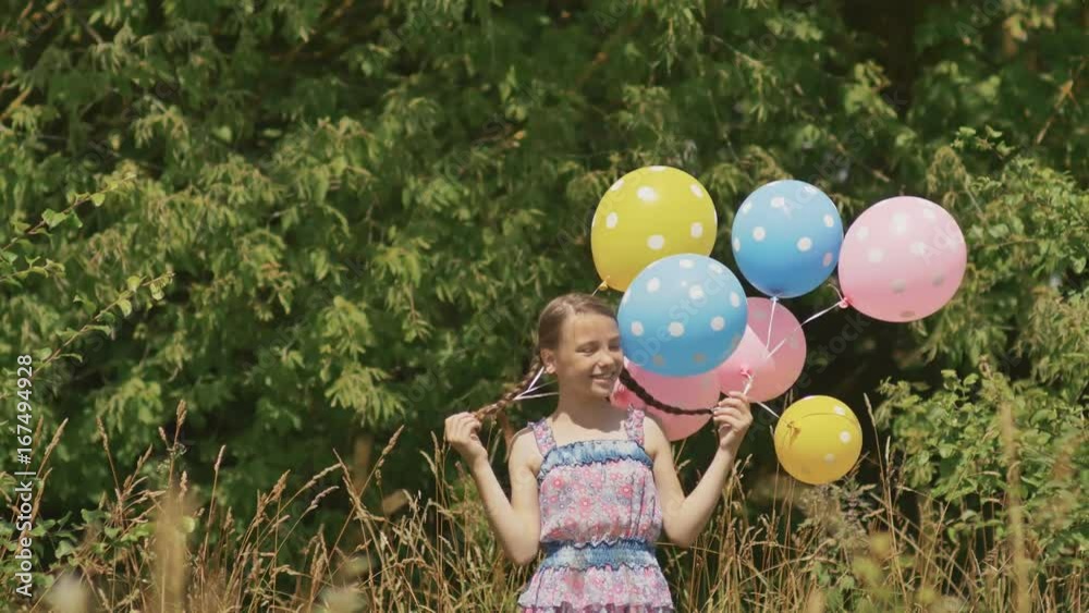 Cheerful and pretty girl with colorful balls attached to her hair and braids on her head. Funny idea with balloons. Cheerful and pretty girl with colorful balls attached to her hair and braids on her head. Funny idea with balloons.