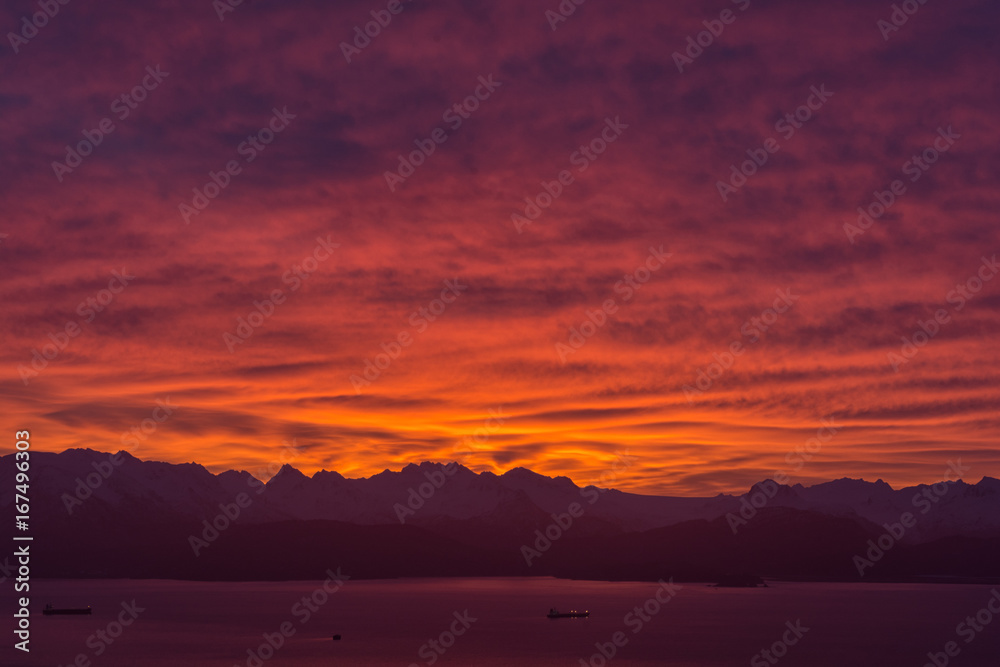 Two ships on Bay with Kenaii Mountains in background under red glowing clouds of sunrise