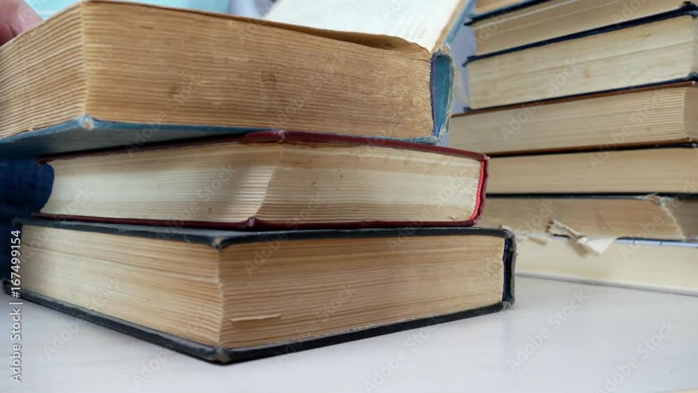 Man Looks Through Stack Of Books On The Table. Ancient Books On Bookshelf. Taking Old Books From A Stack Man Looks Through Stack Of Books On The Table. Ancient Books On Bookshelf. Taking Old Books From A Stack