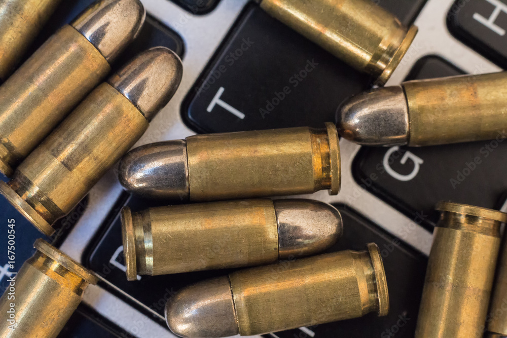 Gun control concept. Close up of bullets and laptop keyboard
