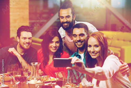 friends taking selfie by smartphone at restaurant