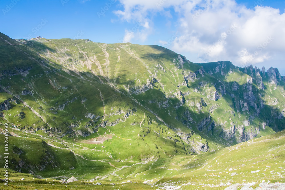 Panoramic view over the Carpatian mountains, green valleys and beautiful blue sky at the background, Bucegi natural park, Romania, on sunny summer day.