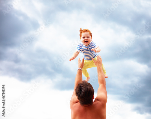 baby delighted with happiness is thrown by dad up in the sky