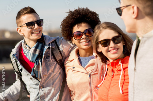 happy teenage friends in shades talking on street