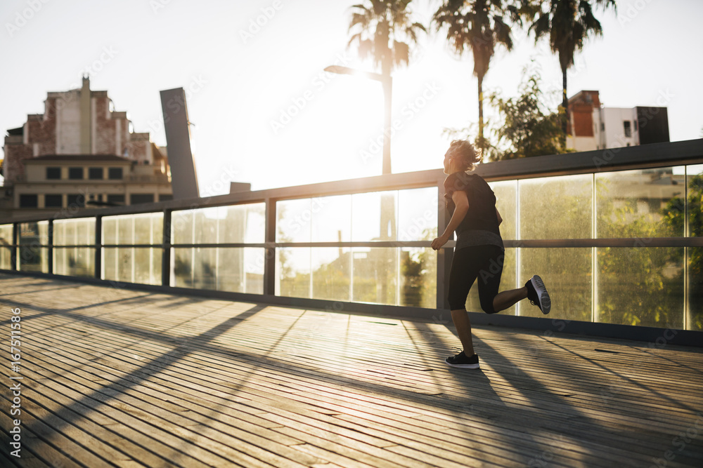 Rear view of woman jogging on bridge during sunset Rear view of woman jogging on bridge during sunset