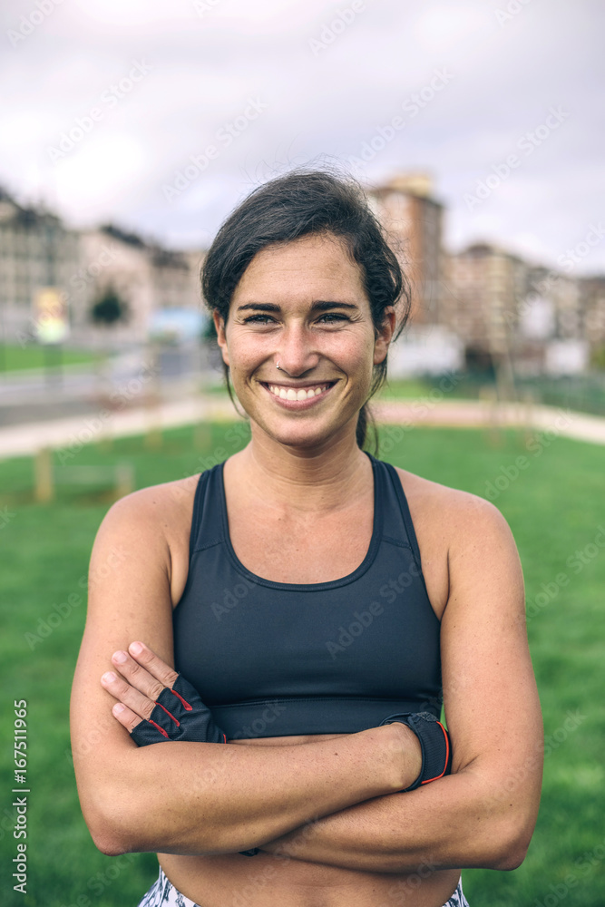 Happy sportswoman with arms crossed standing at park Happy sportswoman with arms crossed standing at park