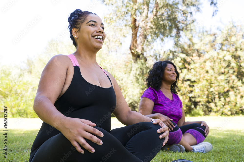Low angle view of happy female friends meditating while sitting at park Low angle view of happy female friends meditating while sitting at park