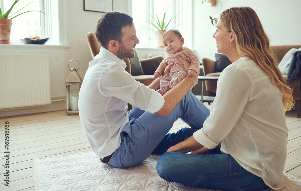 Φωτογραφία Smiling young parents sitting with their baby girl at home