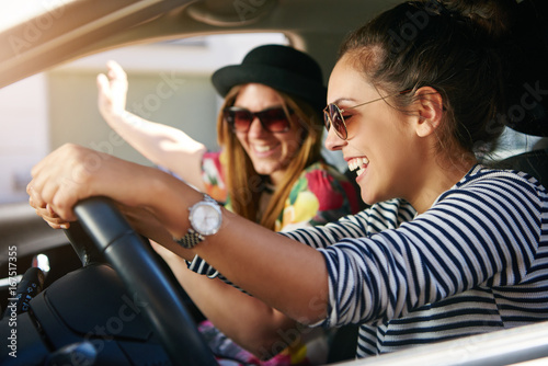 Obraz na plátně Two smiling young friends driving on a road trip together