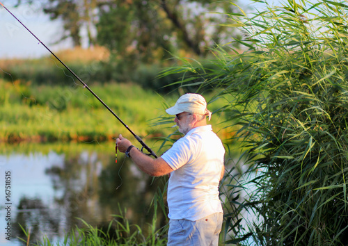 мужчина ловит рыбу на берегу реки.летняя рыбалка