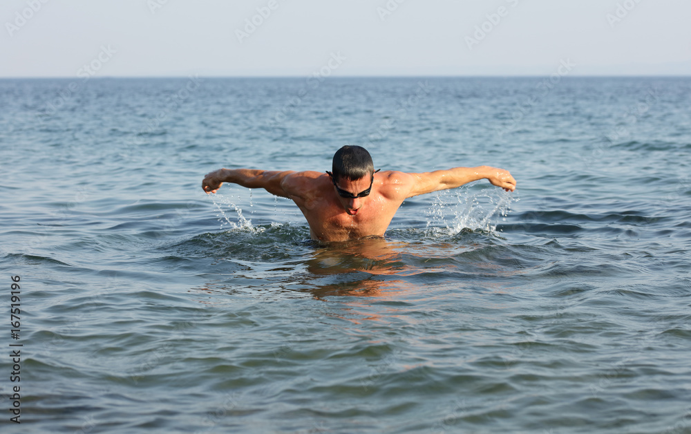 Strong muscular man swimming i butterfly style. Active summer holiday vacation. Sport, healthy lifestyle concept