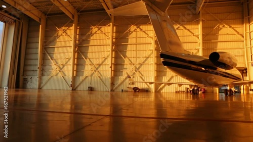Beautiful pan of private jets parked in aircraft hangar and outside during Sunset