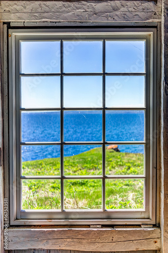 Fototapeta Patrzejący przez starego okno dom z falezą i widok na ocean w Bonaventure wyspie, Quebec, Kanada
