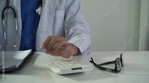 Healthcare costs and fees concept.Hand of smart doctor used a calculator for medical costs in modern hospital in 4K (UHD).