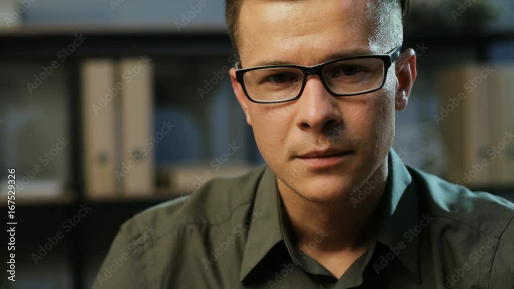 Portrait of attractive young business man in the stylish glasses looking to the camera in the modern office background. Portrait of attractive young business man in the stylish glasses looking to the camera in the modern office background.