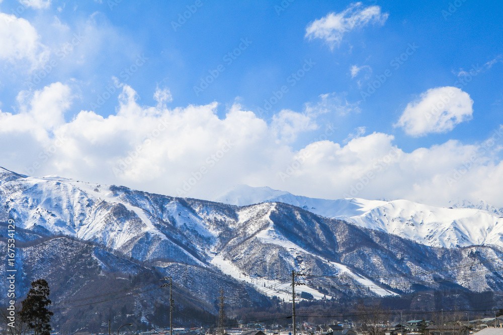 Hakuba mountain range   in the winter with snow on the mountain and blue sky and clouds background in Hakuba  Nagano Japan.