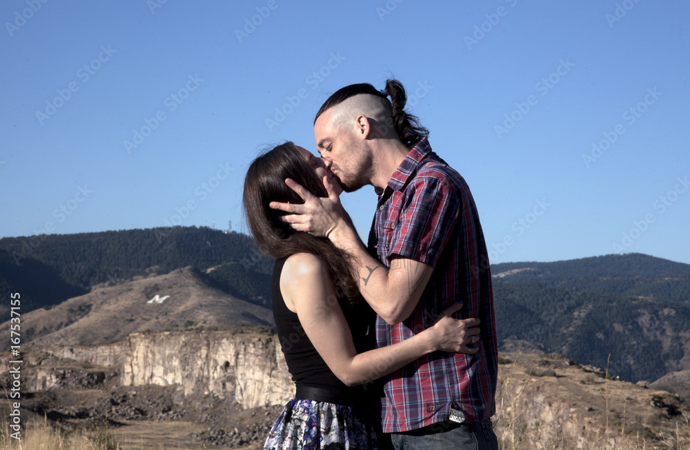 loving young hipster couple embracing each other in the meadow of the Colorado mountains in the morning time