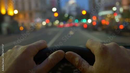 Driving a car through the city POV , hand on steering wheel close up. Dusk, morning, sunset, early or late. Traffic jam. Many cars with light on. 4k
