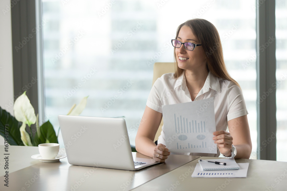 Smiling businesswoman satisfied with fast growing startup, holding financial report with rising statistics, upward charts, increased sales, dreaming of future company prosperity and business success Smiling businesswoman satisfied with fast growing startup, holding financial report with rising statistics, upward charts, increased sales, dreaming of future company prosperity and business success