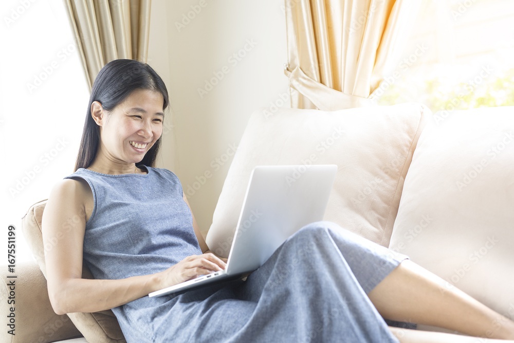 Naklejka premium Working woman sitting on the sofa.She is working with a mac book. concept women working with technology.