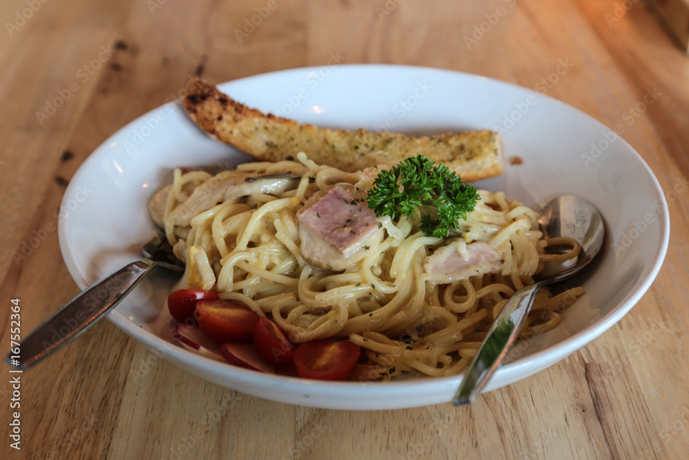 Spaghetti carbonara in white dish on wooden table.