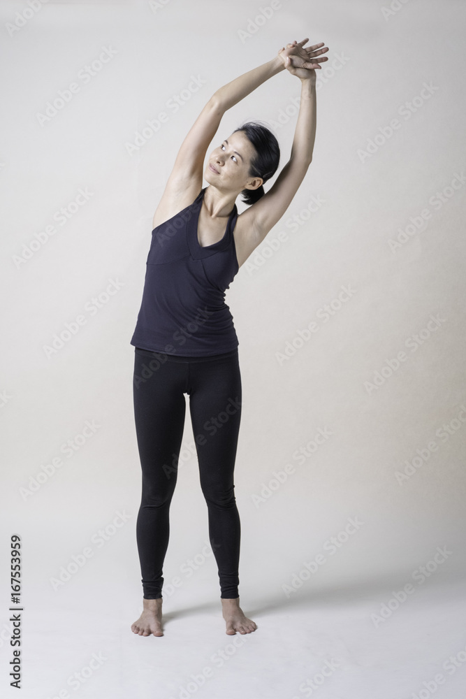 Fototapeta premium Portrait of mid Asian woman is playing yoga in studio in black sport wear.