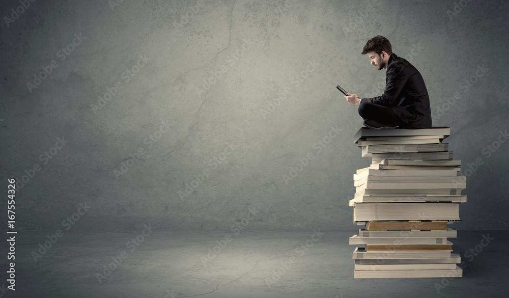 Student sitting on pile of books Student sitting on pile of books