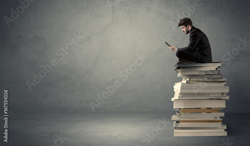 Student sitting on pile of books