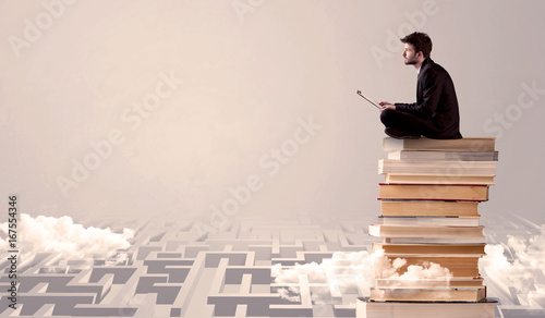 Man with tablet sitting on books
