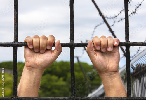  hands of a man behind bars