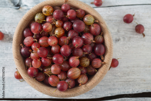 Red gooseberry in a bowl on wooden surface