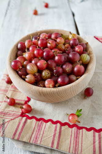 Red gooseberry in a bowl on wooden surface