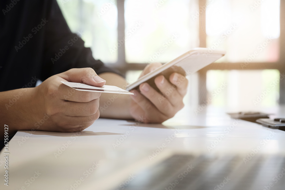 © Prathankarnpap - Hands holding credit card and entering security code using smart phone online shopping concept.