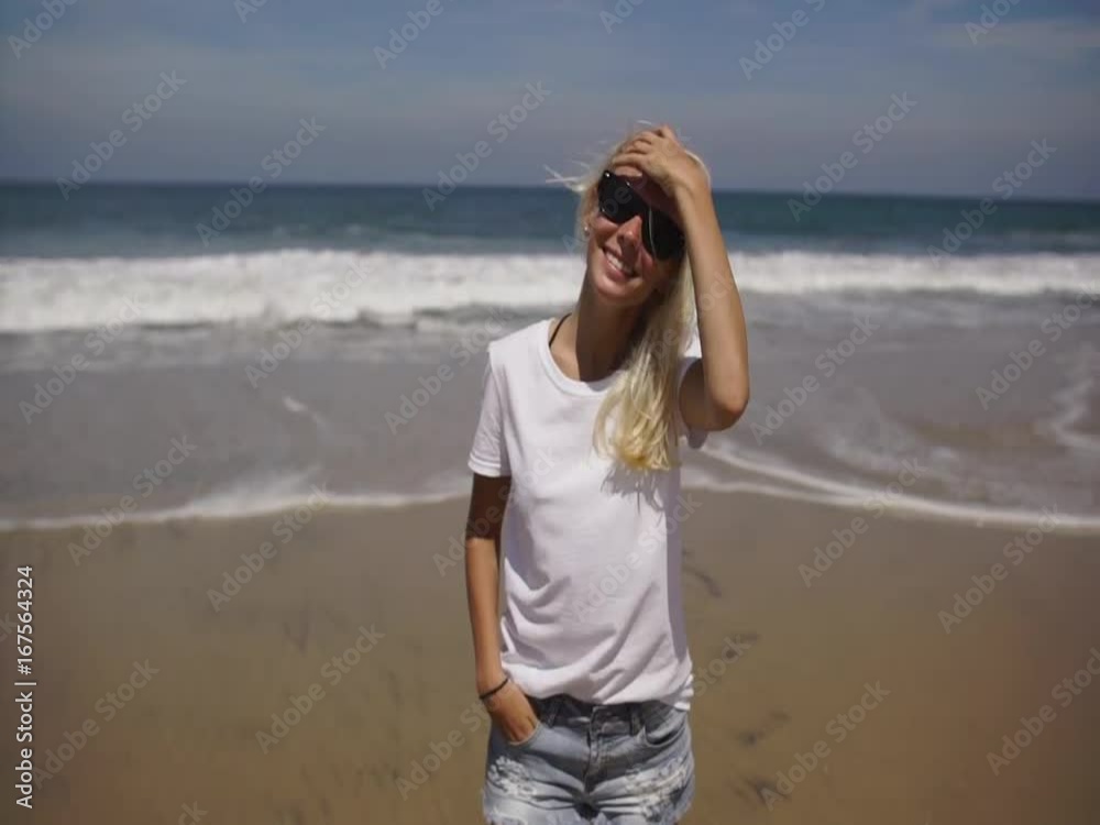 Yong woman walking on beach looking at camera and smiling Yong woman walking on beach looking at camera and smiling