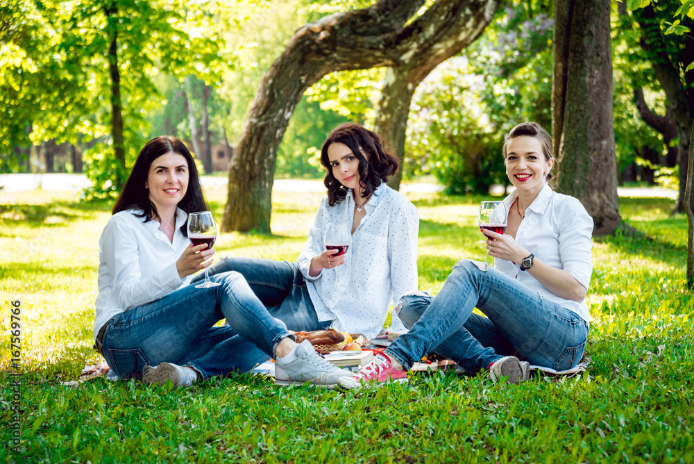 Young beautiful girls with glass of red wine in the park Young beautiful girls with glass of red wine in the park