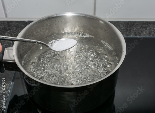 Salz in das kochende Wasser werfen