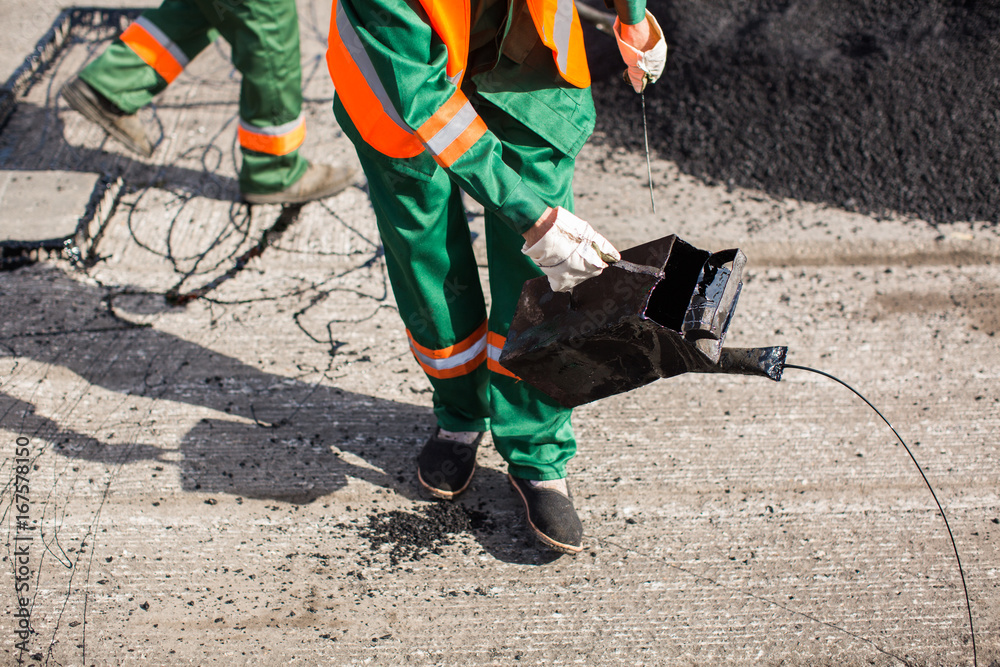 The man working asphalt pouring tar for road repair The man working asphalt pouring tar for road repair