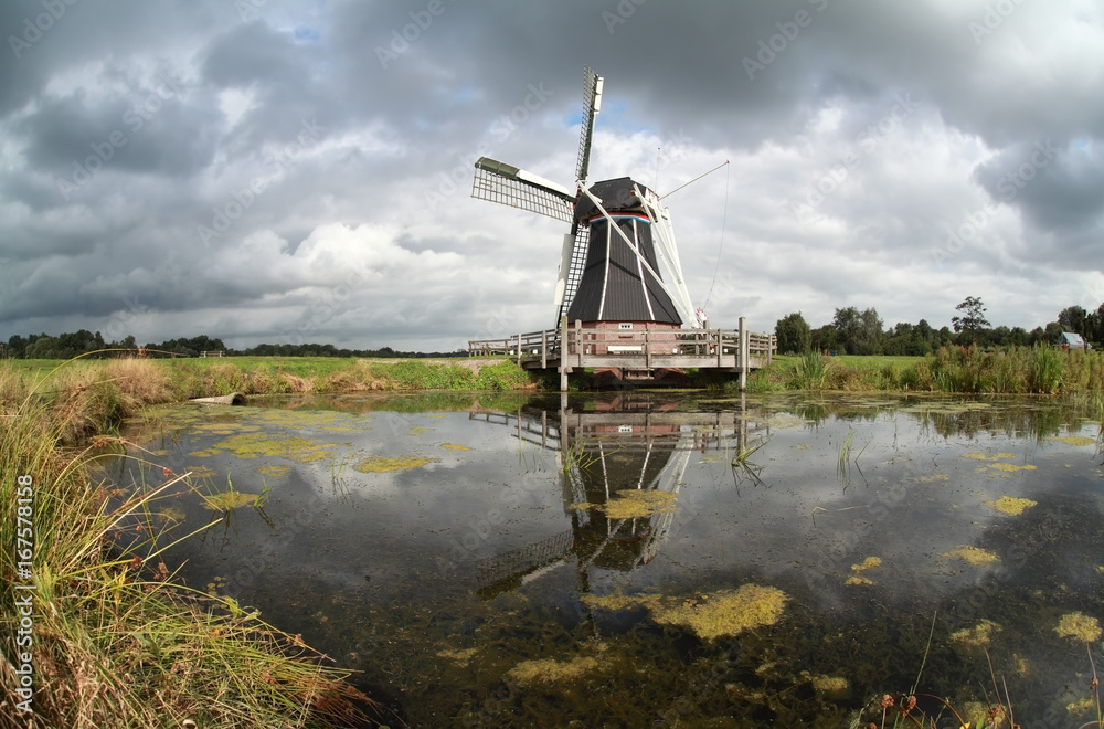 Fototapeta premium windmill reflected in lake water
