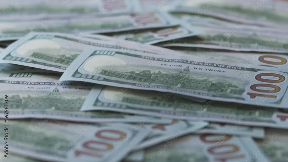 Slow motion hundred dollar bills falling on table Slow motion hundred dollar bills falling on table