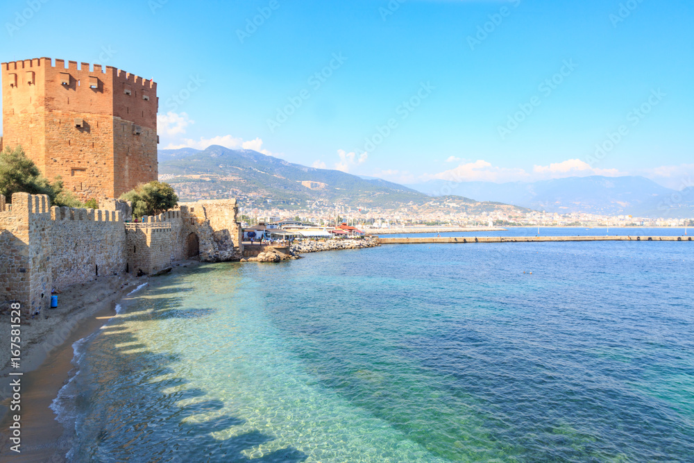 Kizil (red) tower with alanya fortress with alanya city background with mountains