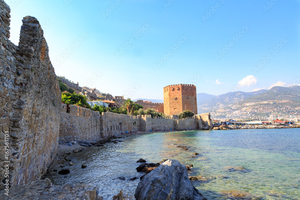 Kizil (red) tower with alanya fortress with alanya city background with mountains