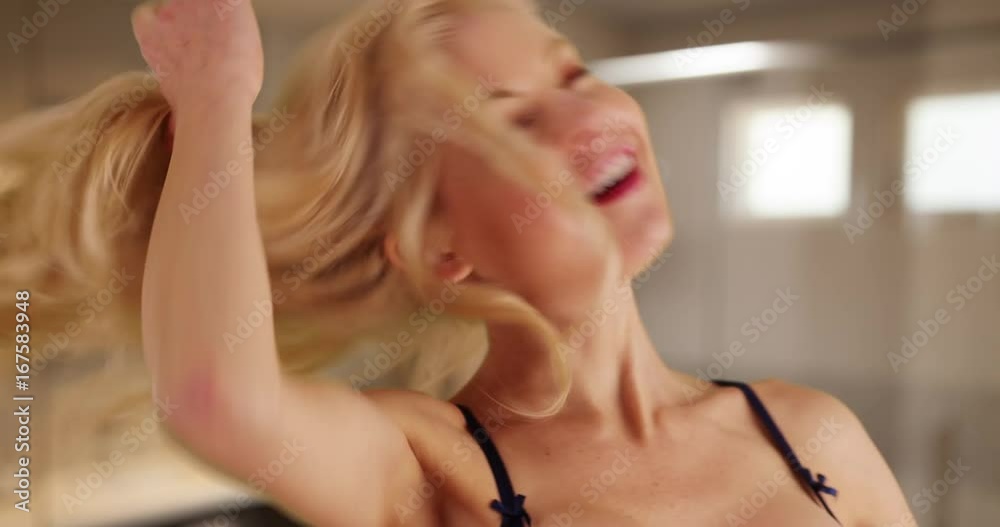 Close up of cheerful Caucasian woman letting down her hair shaking it out playfully inside bathroom. Close-up of attractive female loosening her curls looking at camera laughing. 4k 