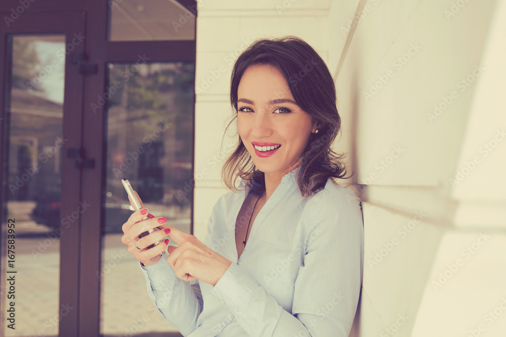 Happy woman with mobile phone smiling standing outside apartment condo complex. Happy woman with mobile phone smiling standing outside apartment condo complex.