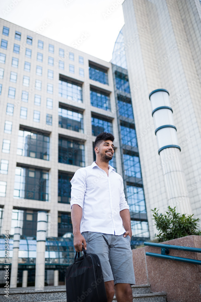 Young handsome Afro American man standing in front of huge modern business building. Young handsome Afro American man standing in front of huge modern business building.