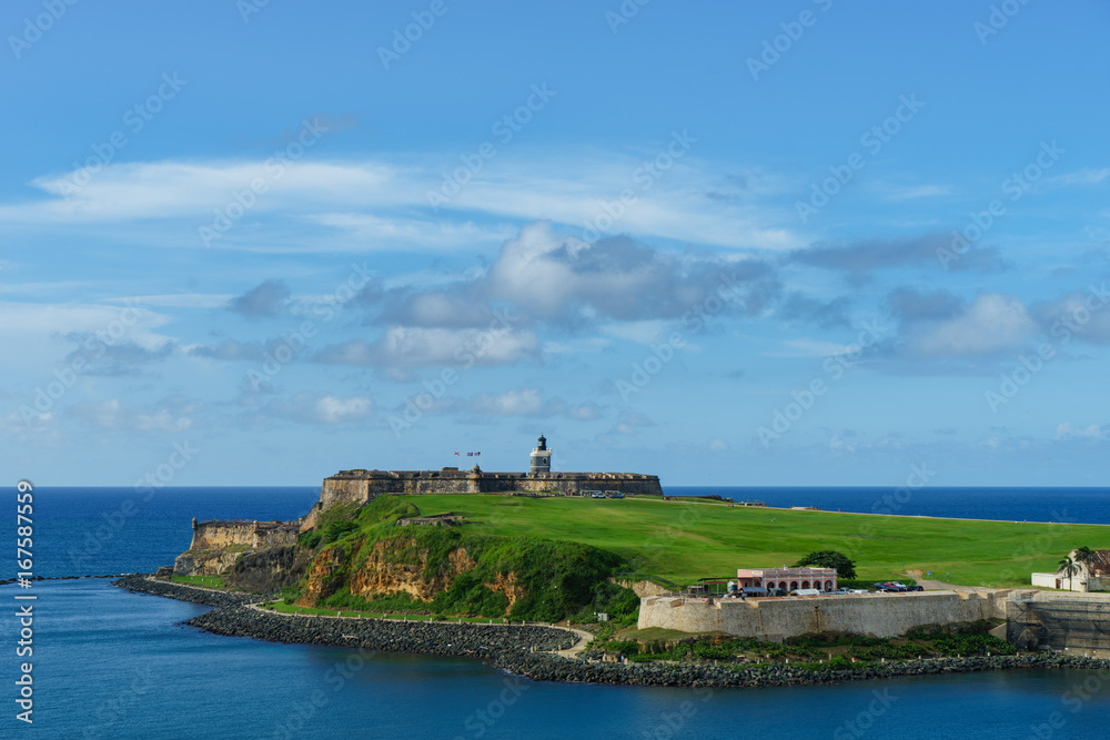 Scenic view of historic colorful Puerto Rico city in distance with fort in foreground from the sea (cruise ship)