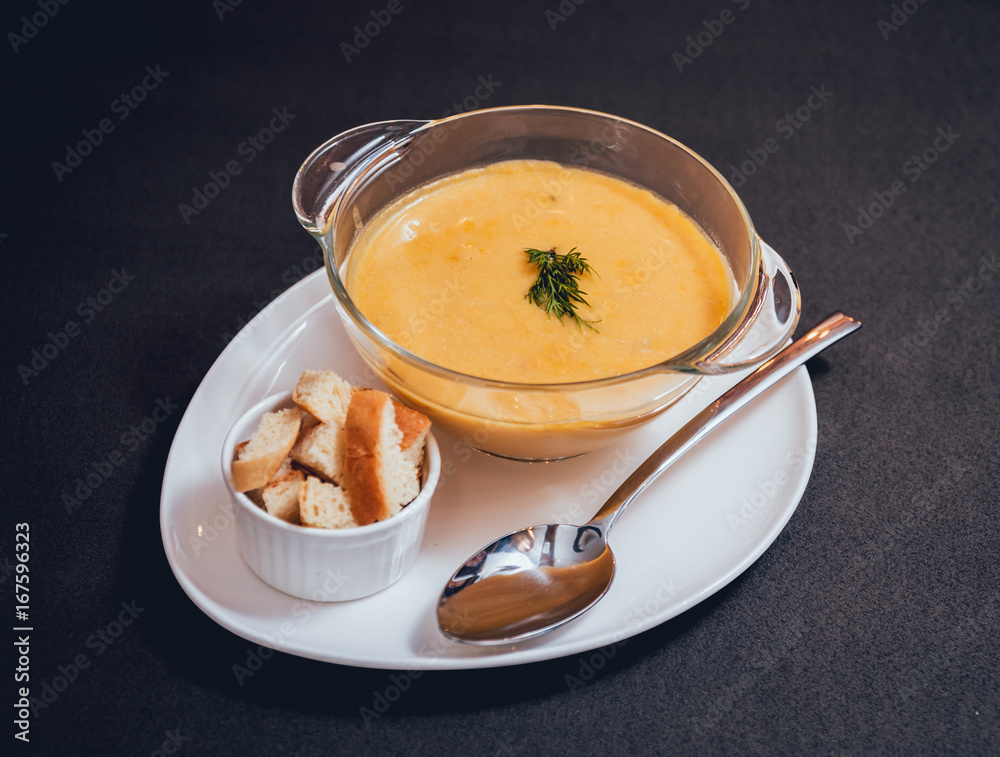 Pumpkin and carrot soup with cream and parsley on dark background. Pumpkin and carrot soup with cream and parsley on dark background.